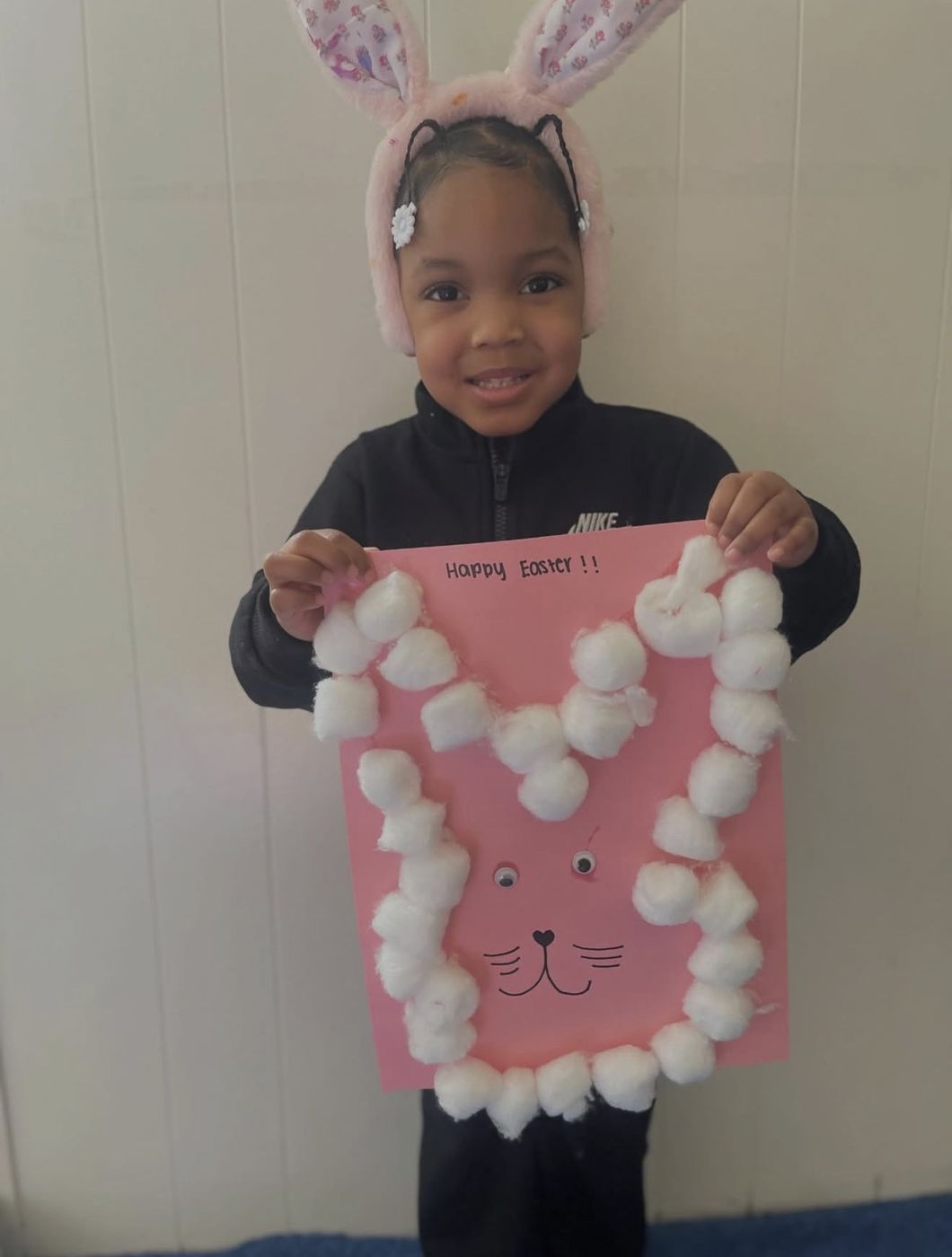 Girl wearing bunny ears with a cotton-ball Easter craft