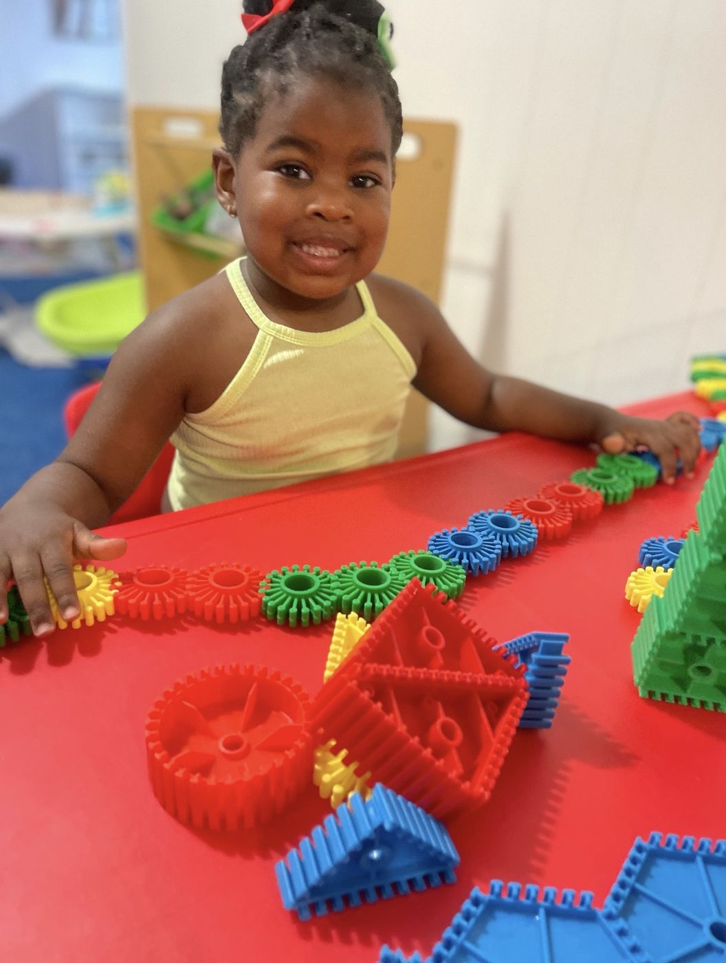 Toddler playing with colorful building toys at Happy Hearts & Faces Day Care